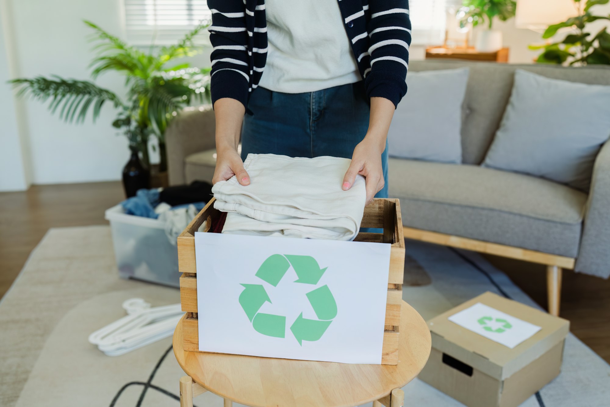 Asian women sort clothes from old clothing box to recycle. Recycling clothes concept