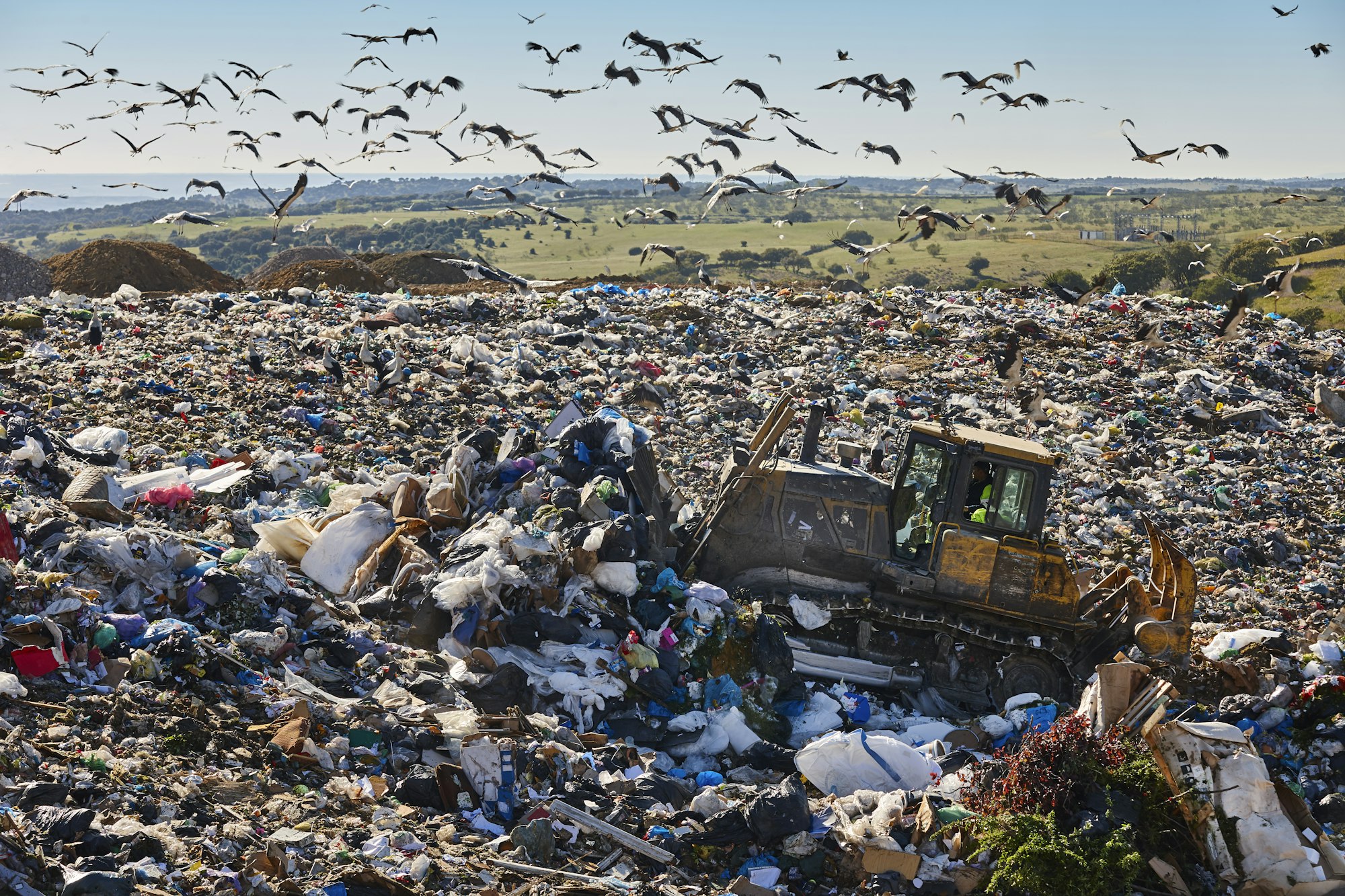 Heavy machinery shredding garbage in an open air landfill. Pollution