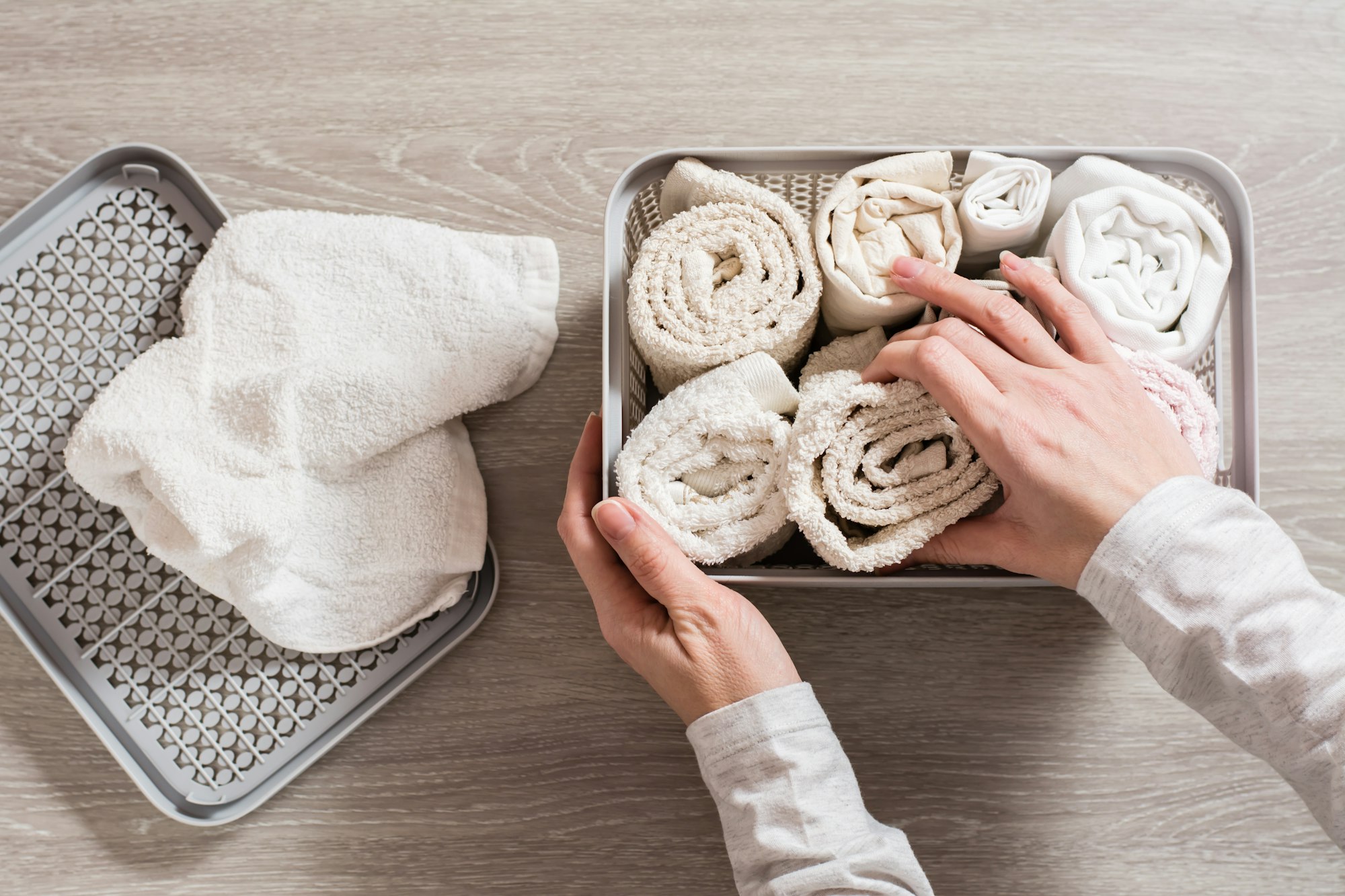 Women's hands neatly fold towels in a clothes drawer. Organization and order at home. Top view