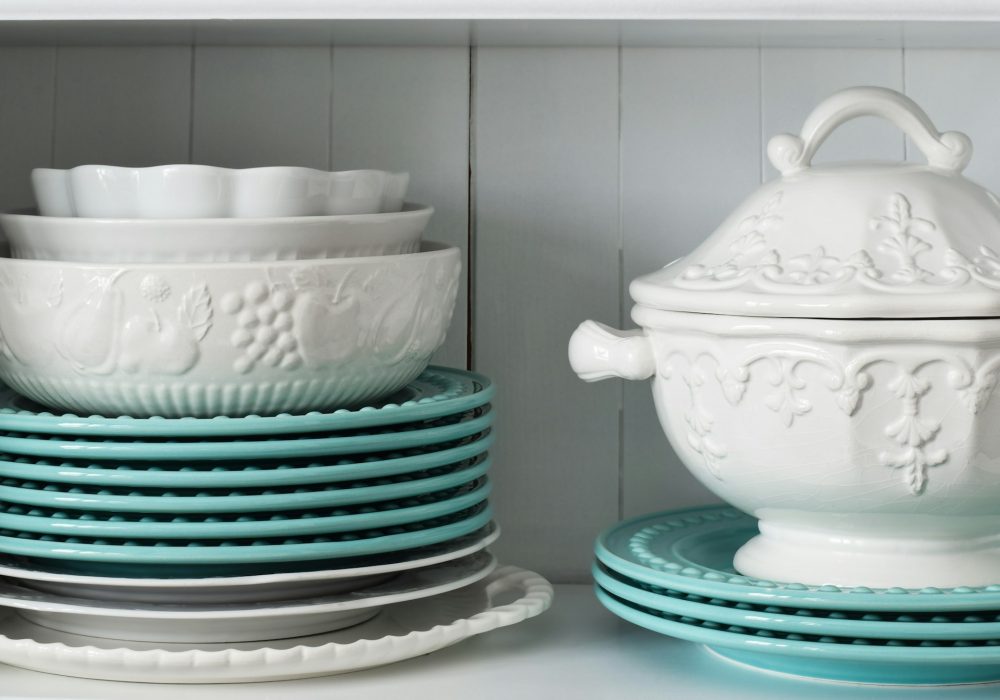 A stack of white and turquoise dishes in a cupboard