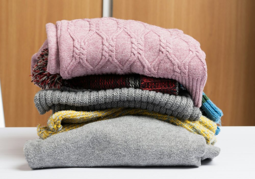 Stack of clean folded clothes on white table, help and volunteering concept