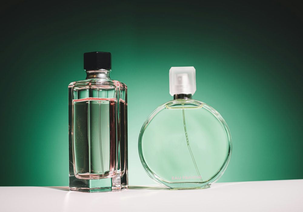 Woman perfume bottles on green background. Choice perfume