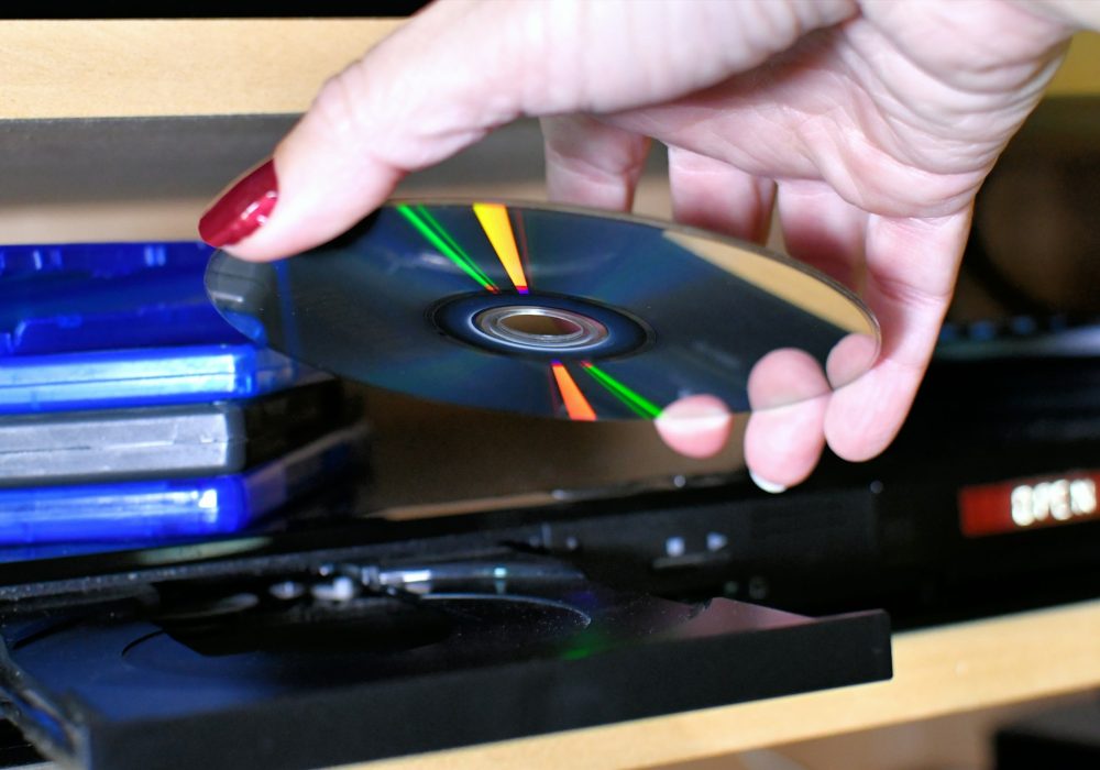 Woman putting a Blu-ray DVD disc into a player for movie night.